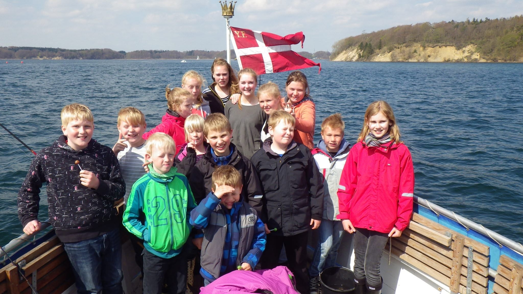 En gruppe børn og unge samlet på en båd under en tur på vandet